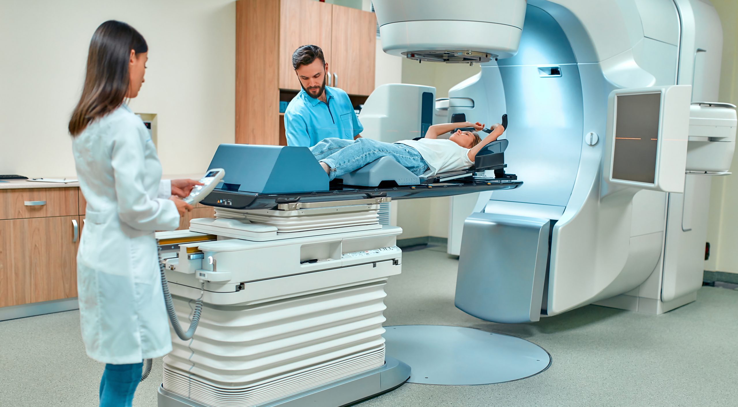 A young woman is undergoing radiation therapy for cancer under the supervision of doctors in a modern cancer hospital